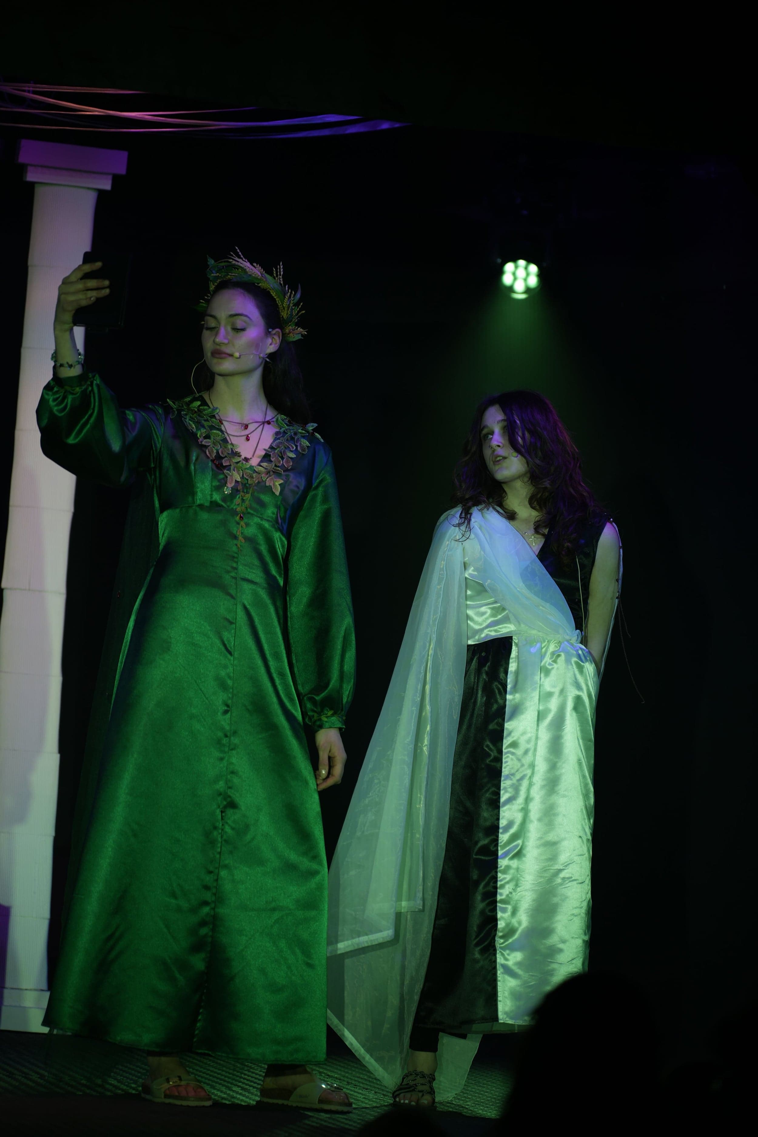 Persephone (Marcella) blickt in einen Spiegel, während Melinoe (Jule) neben ihr steht.